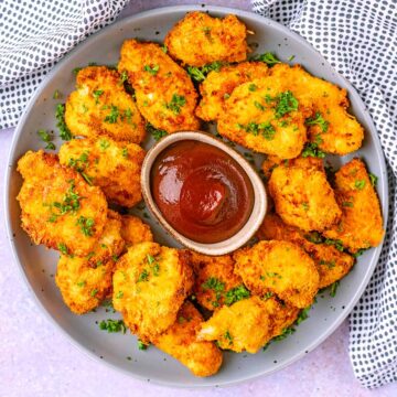 Air Fryer Chicken Nuggets on a plate with some sauce.