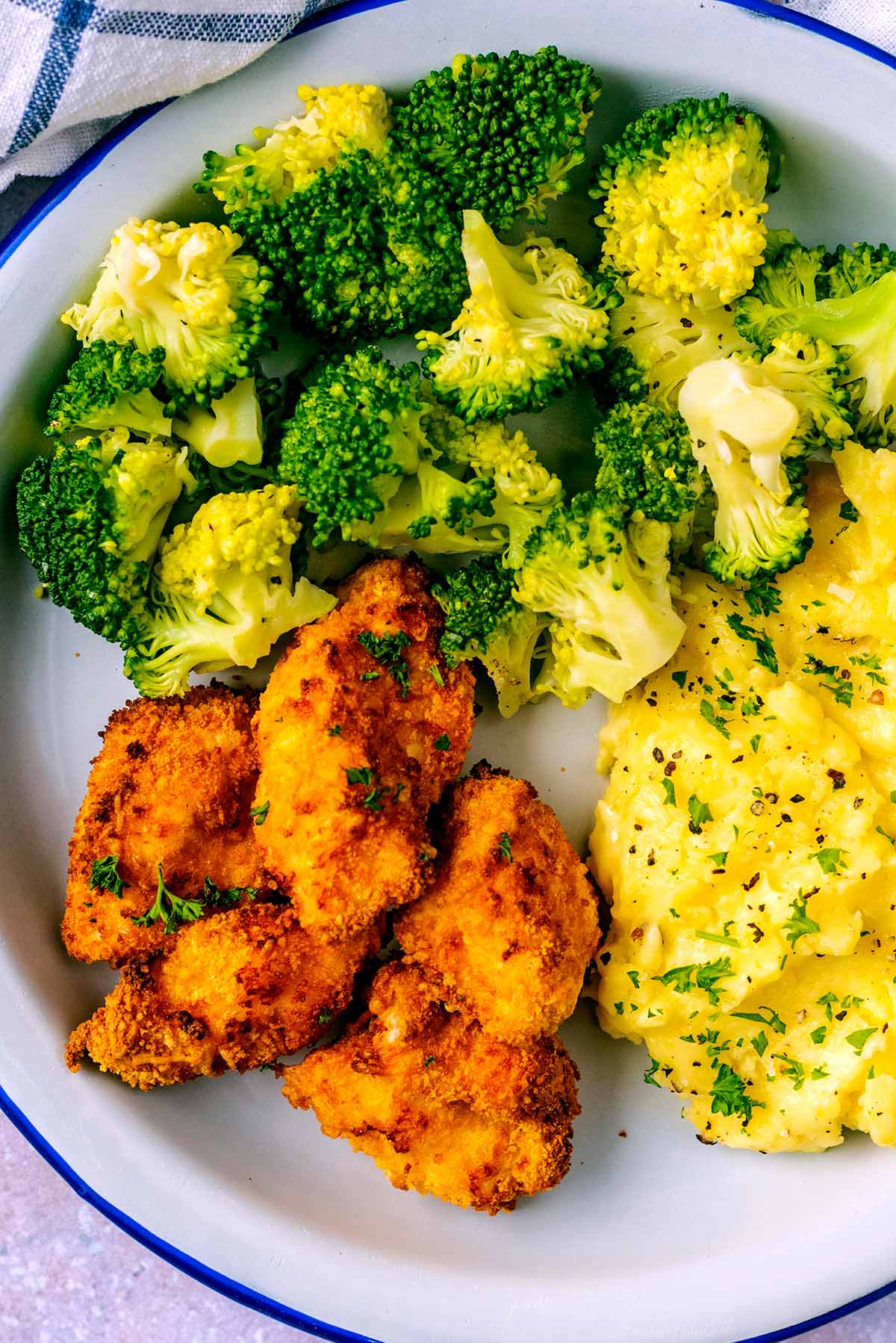 A plate of chicken nuggets, broccoli and mashed potato.