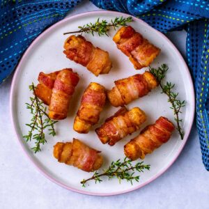 Air fryer pigs in blankets on a plate with some thyme.