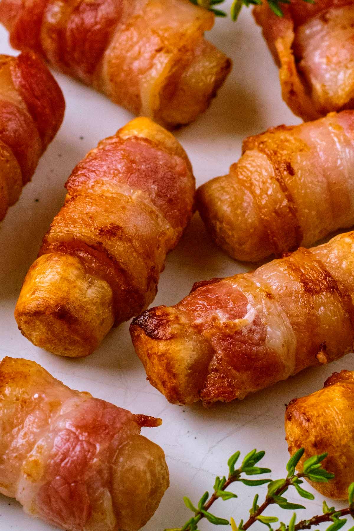 A pile of pigs in blankets on a plate.