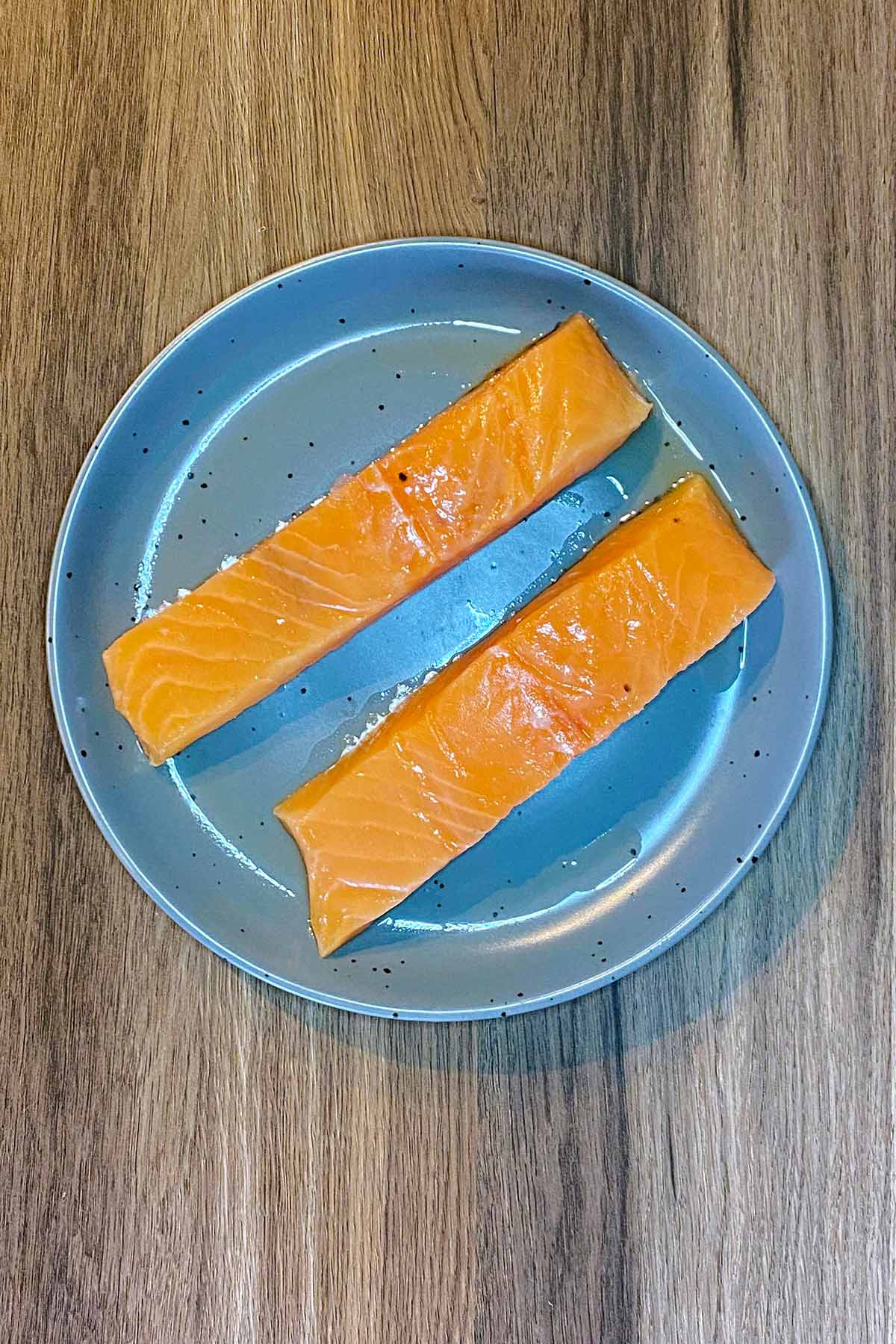 Two raw salmon fillets on a plate.
