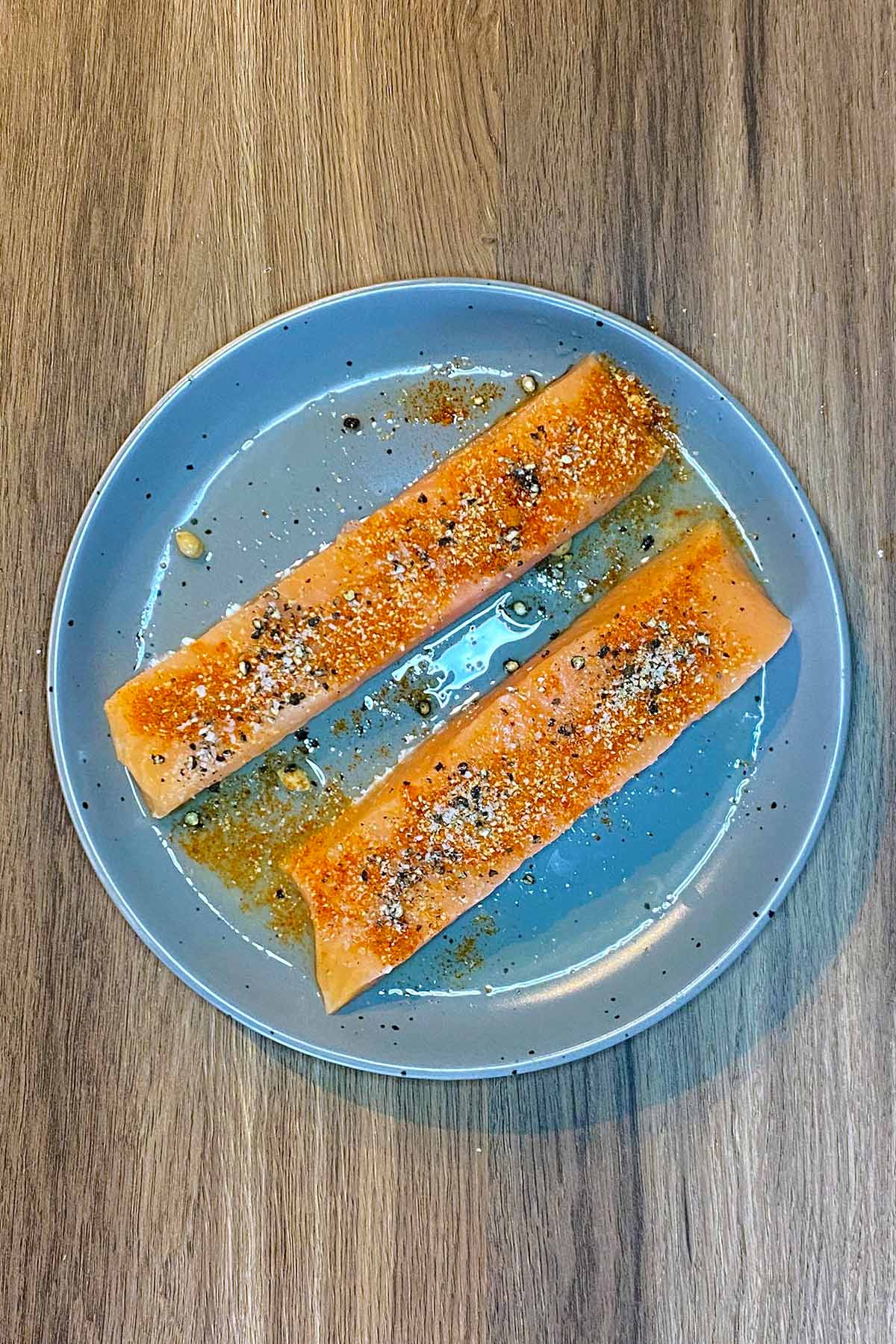 Two salmon fillets coated in seasoning.