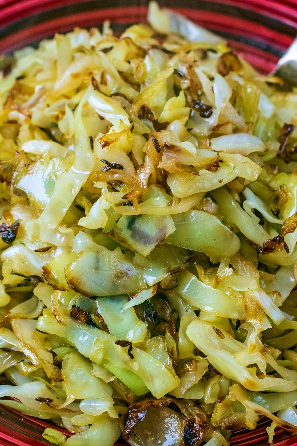 Cooked shredded cabbage with cumin seeds and sliced garlc.