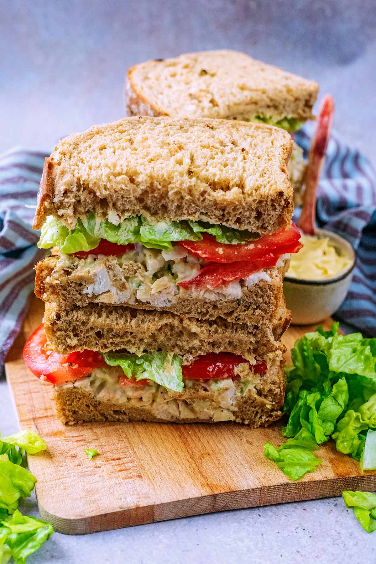 Chicekn salad sandwiches stacked up on a serving board.