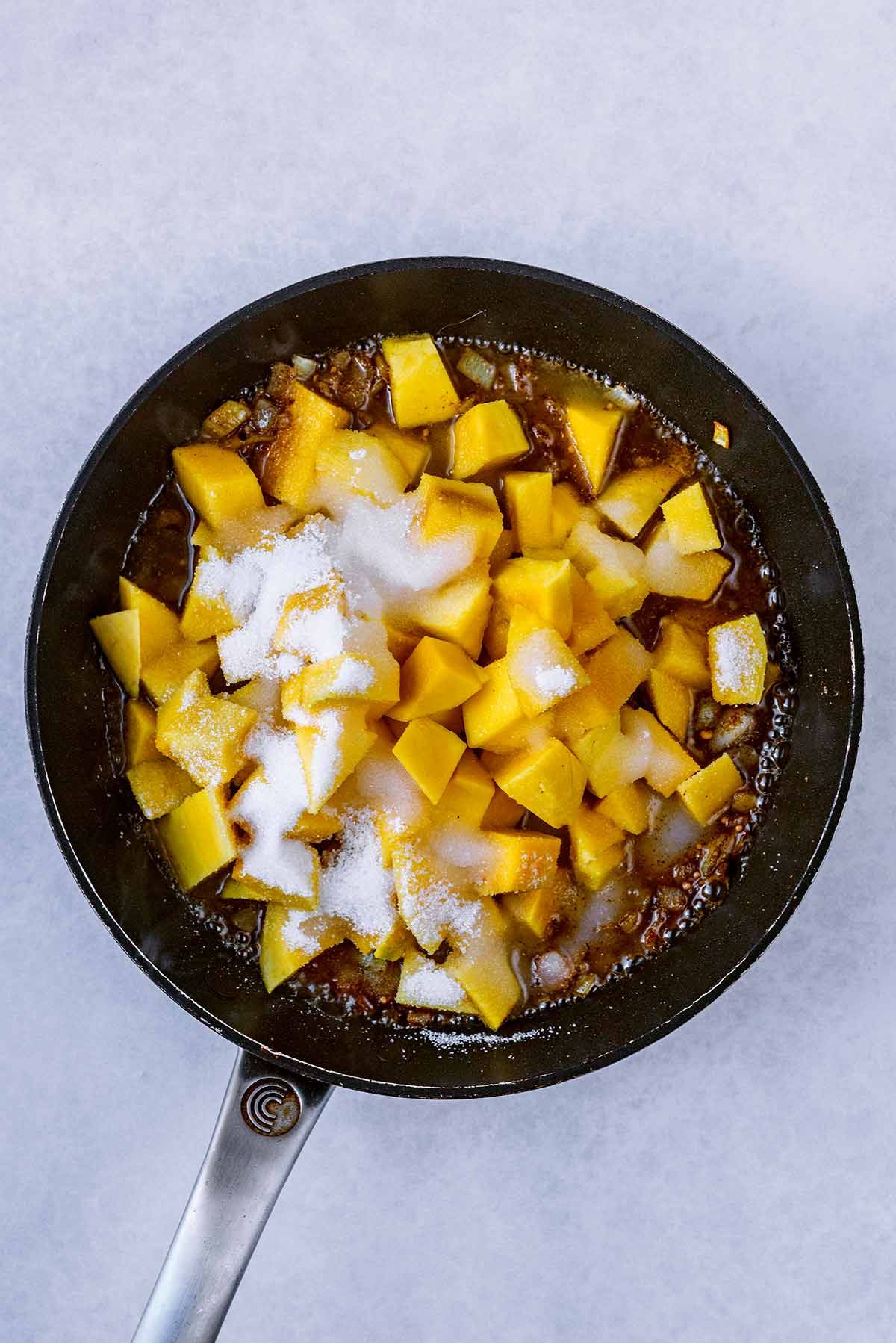 Chopped mango, sugar and vinegar added to the pan.