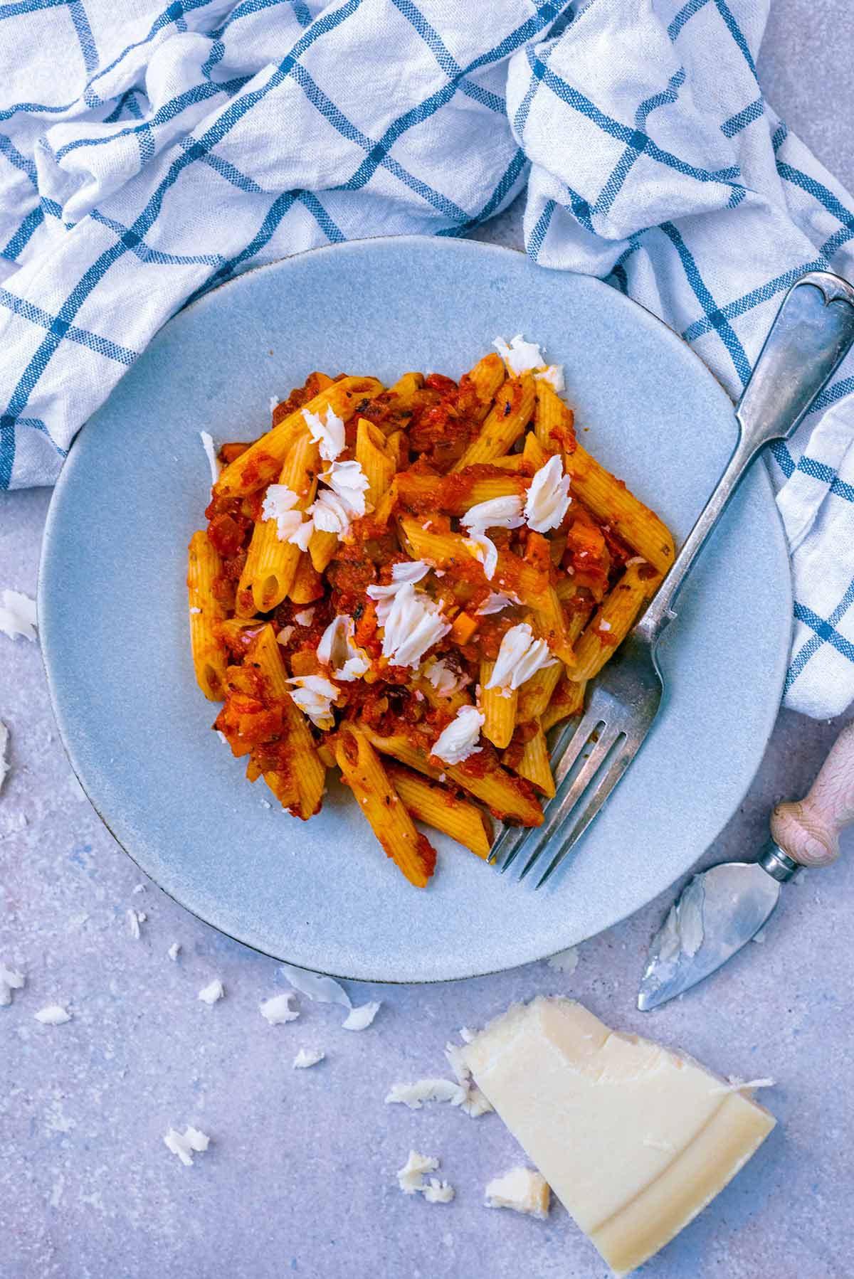 Penne pasta in a tomato sauce with Parmesan shavings on top.