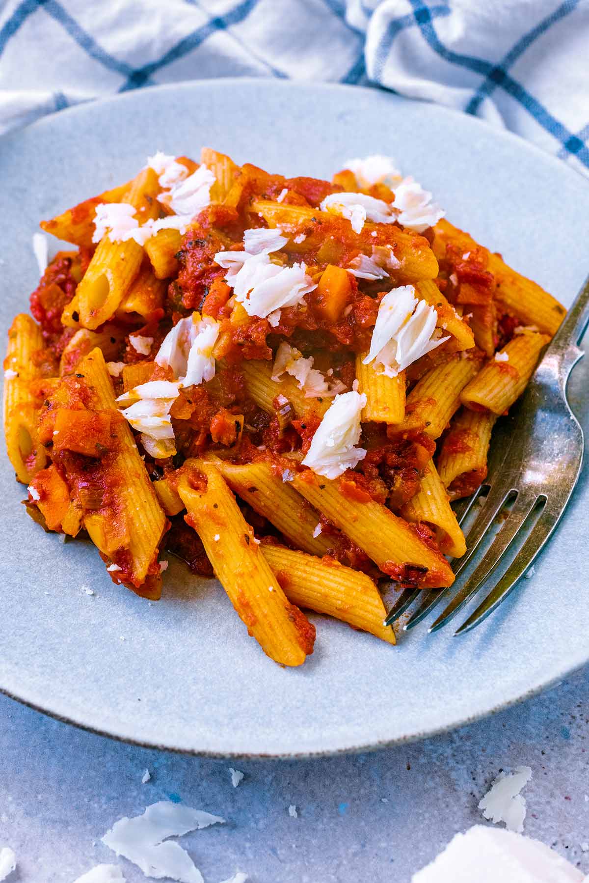A plate of penne arrabbiata in front of a towel.