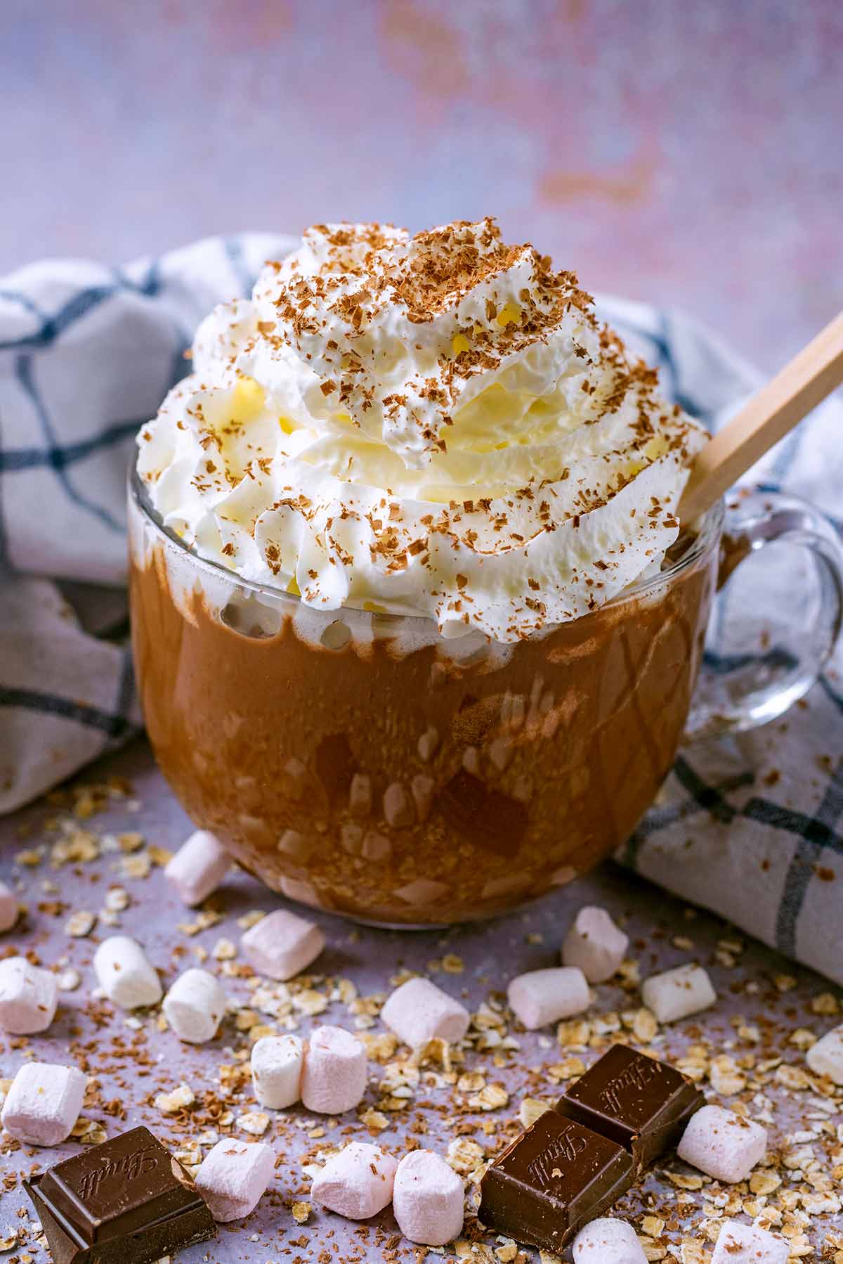 Hot chocolate in a glass mug topped with whipped cream.