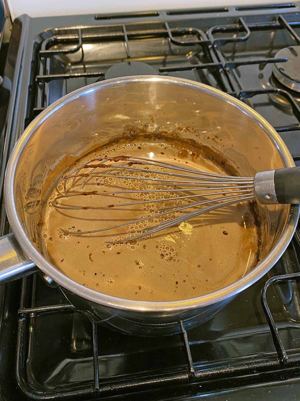 Milk and cocoa powder heating on a hob.