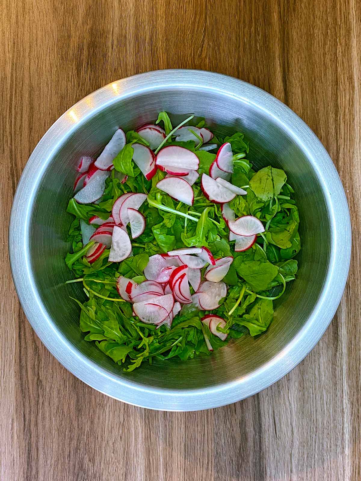 Rocket leaves and sliced radish in a large mixing bowl.