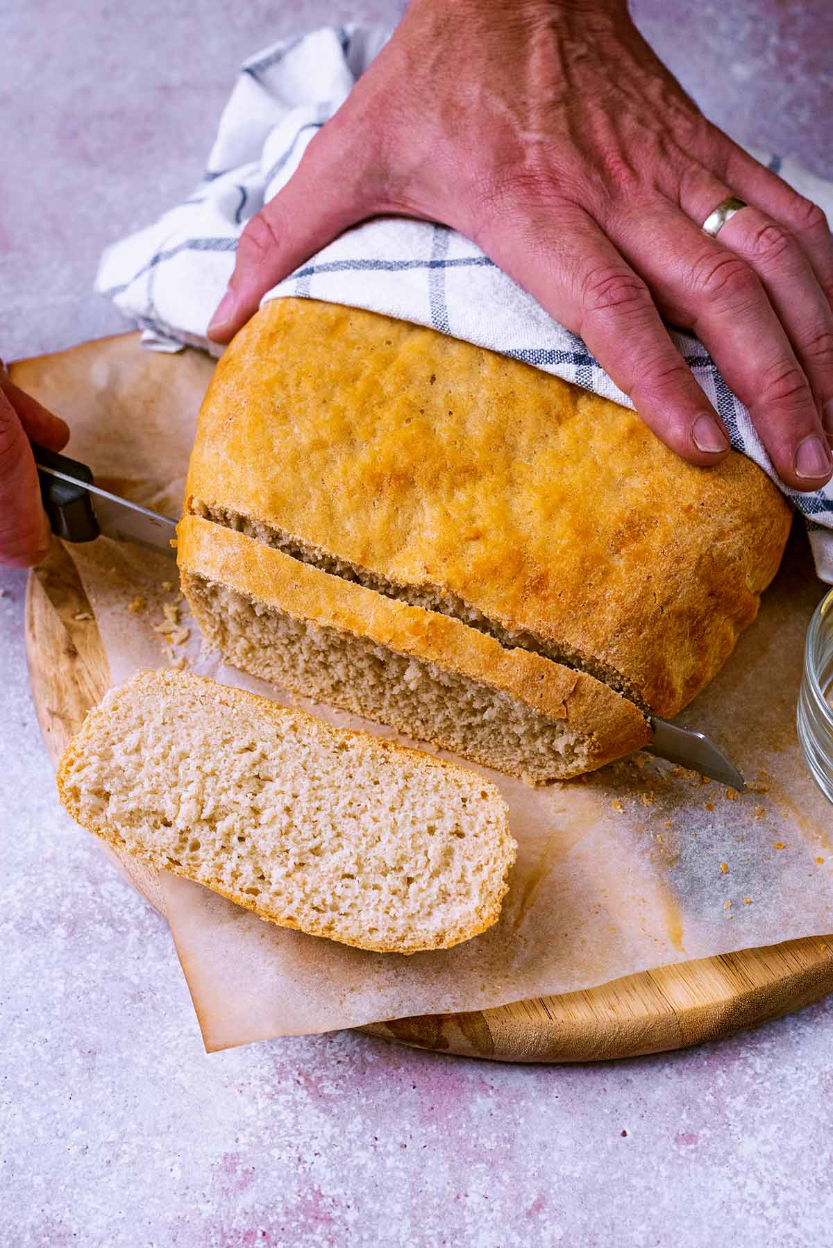 A loaf of bread being sliced by someone with a bread knife.
