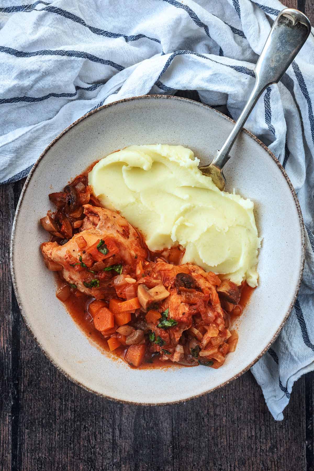 A portion of chicken chasseur in a bowl with mashed potato.