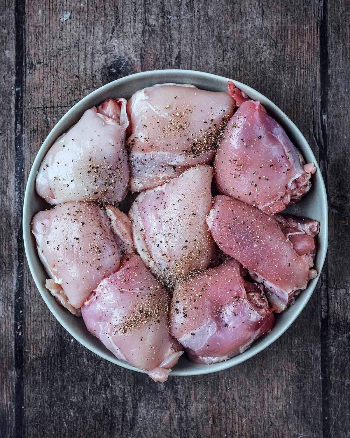 A plate of eight seasoned chicken thighs.