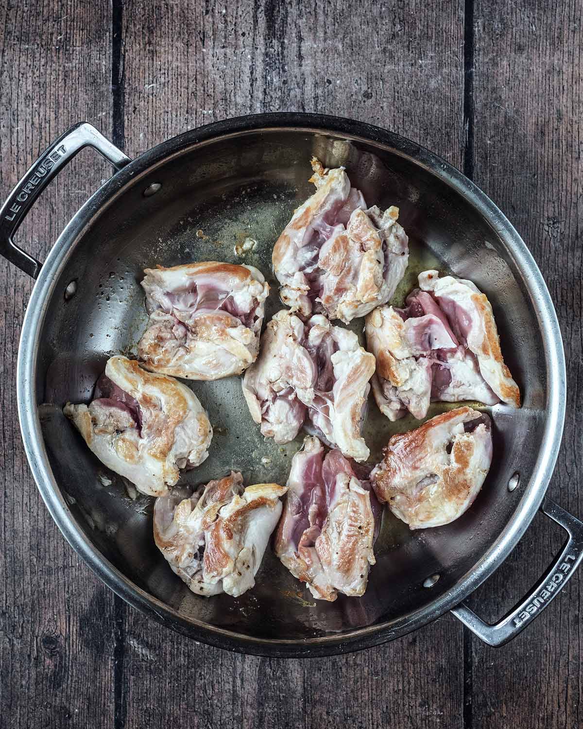 Browned chicken thighs in the pan.