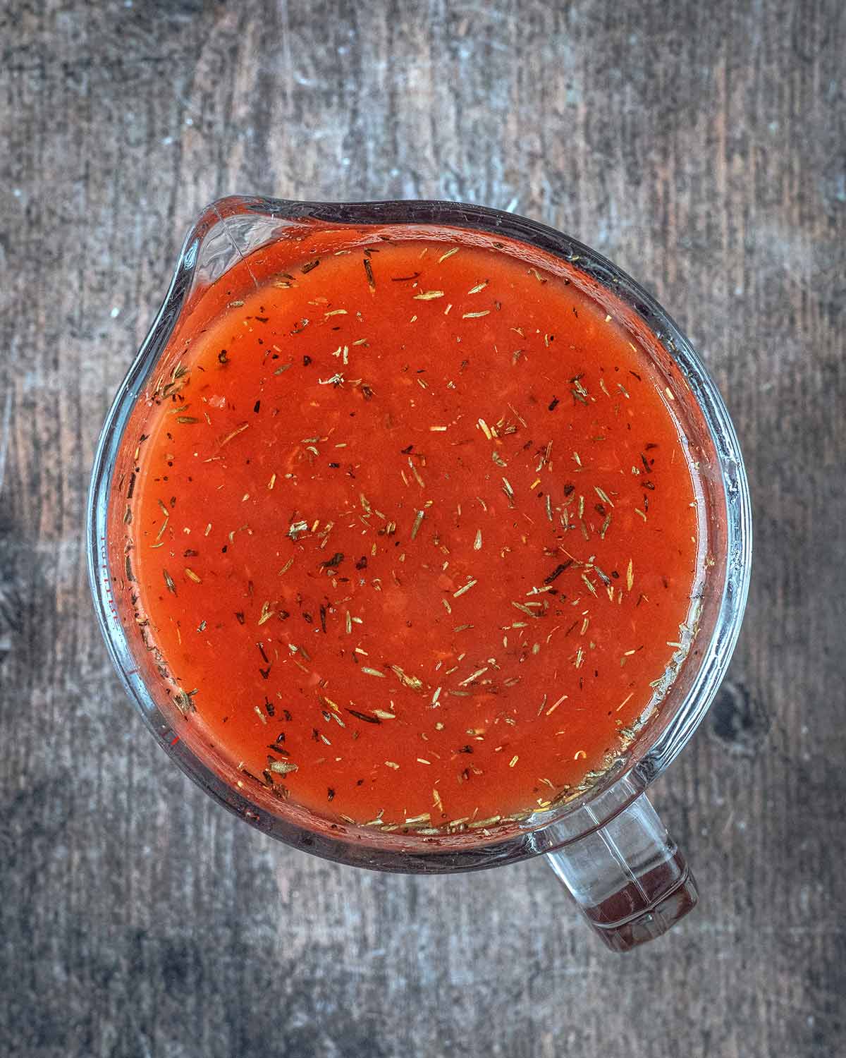 A glass jug full of tomato based stock.