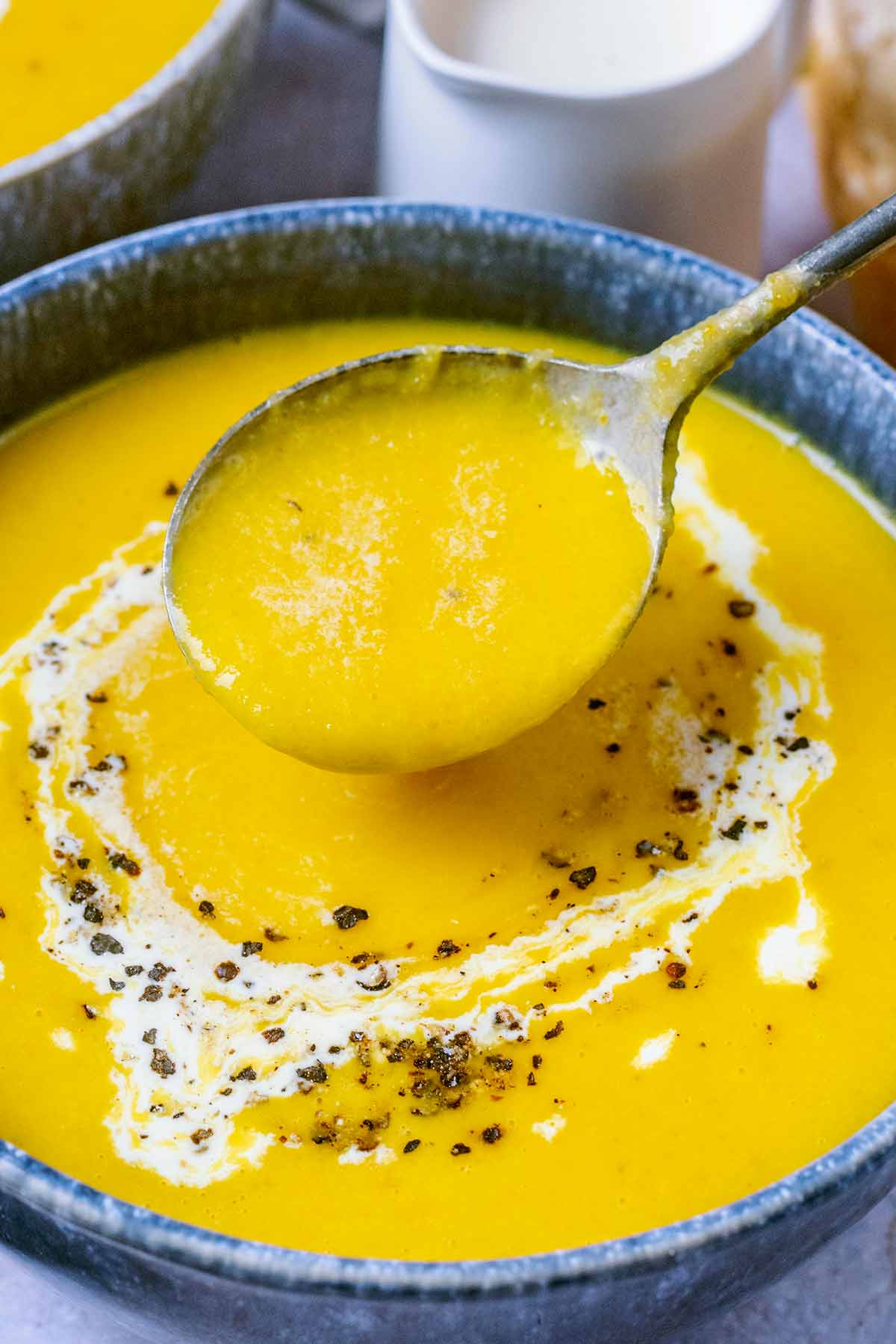 A soup spoon lifting some soup out of a bowl.