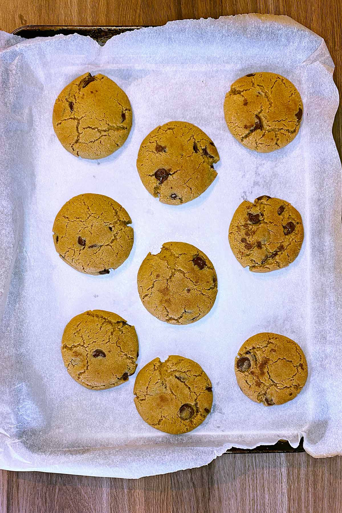 Nine cooked cookies on a baking sheet.