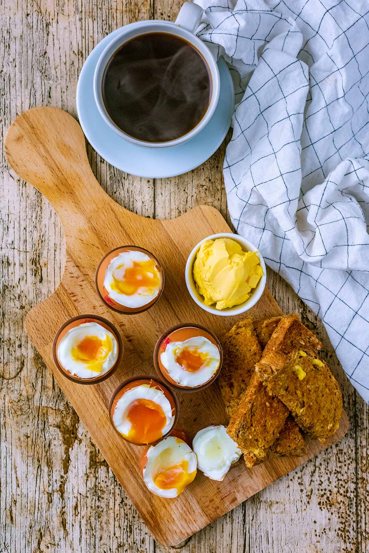 Four soft boiled eggs in egg cups each with their tops cut off.