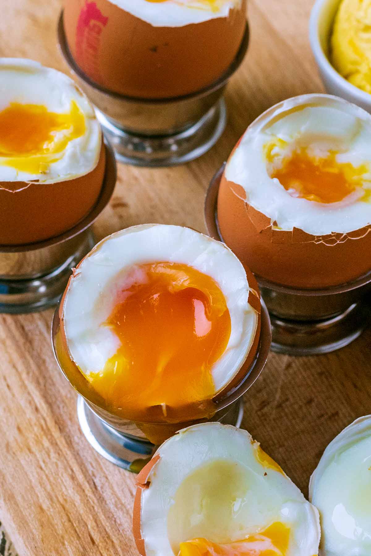 A boiled egg in an egg cup, top removed and yolk dripping out.