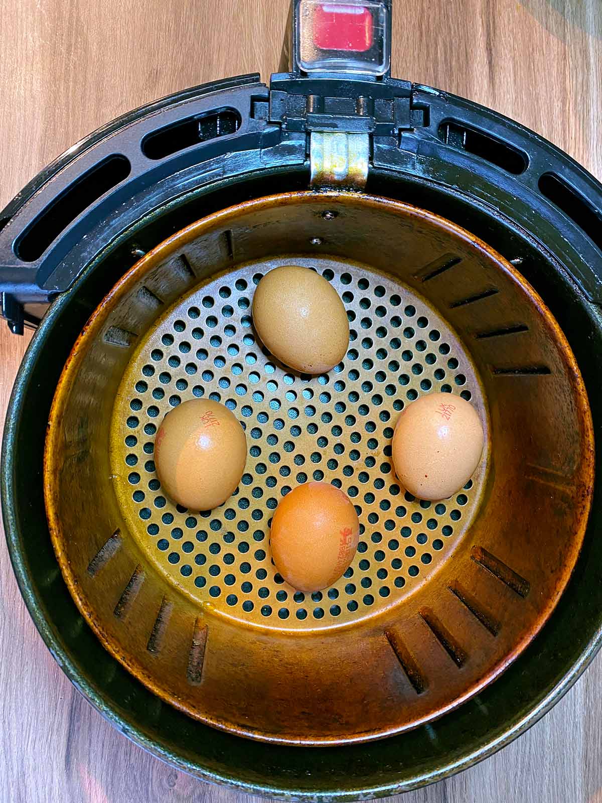 Four eggs in an air fryer baasket.