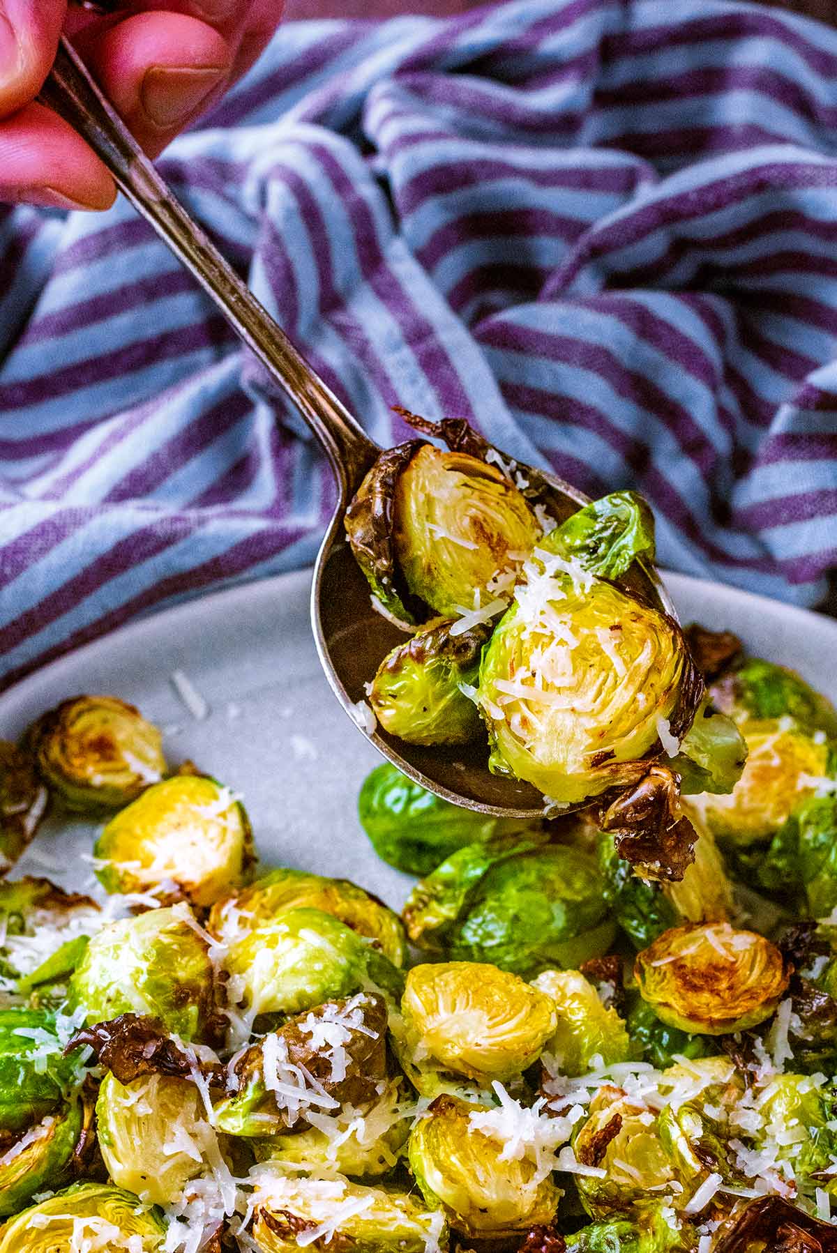 A spoon lifting up cooked Brussels sprouts from a dish.