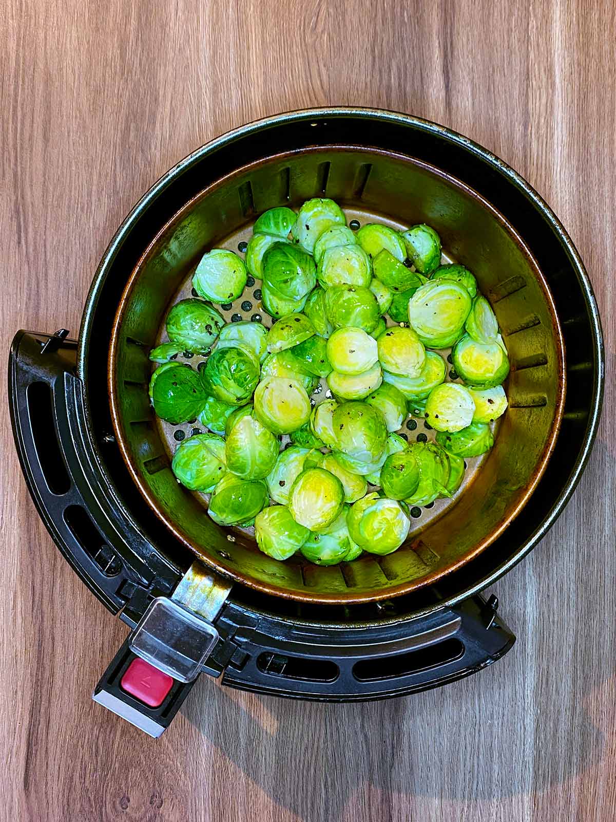 An air fryer basket containing the sprouts.