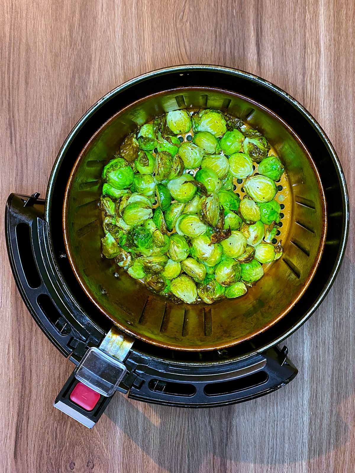 Cooked Brussels sprouts in an air fryer basket.