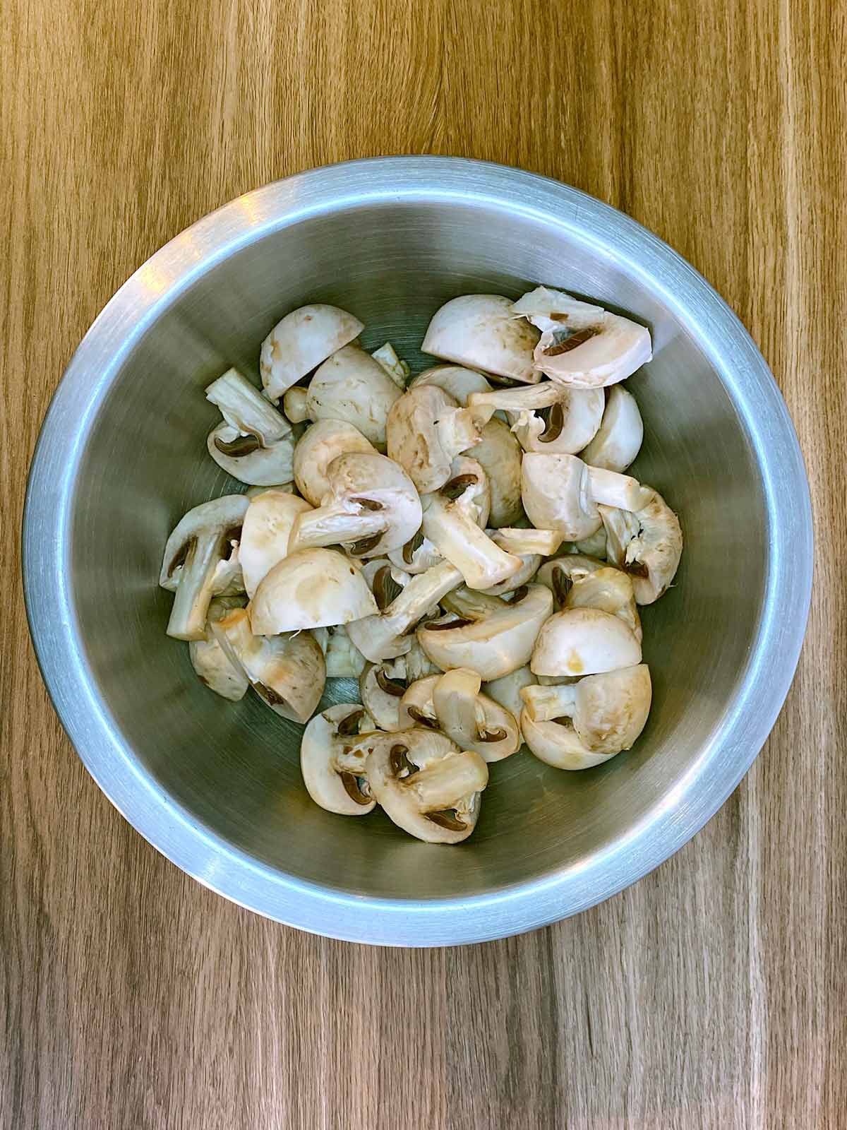 Halved mushrooms in a mixing bowl.
