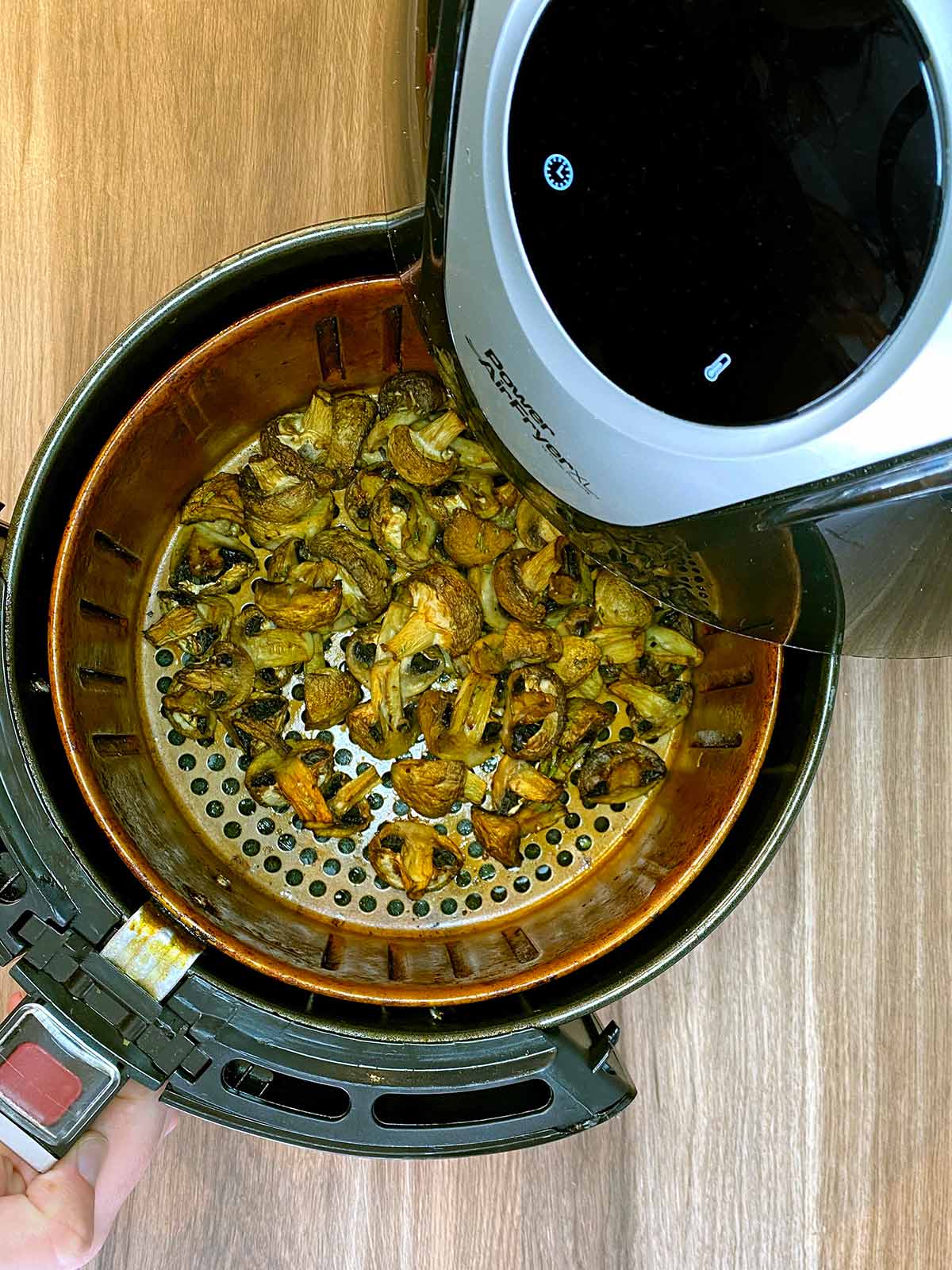 Cooked mushrooms in an air fryer basket.