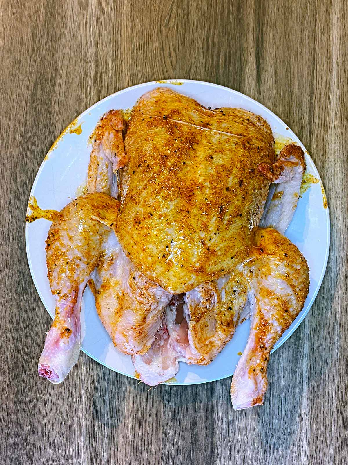 A whole raw chicken smothered in oil, garlic and paprika.