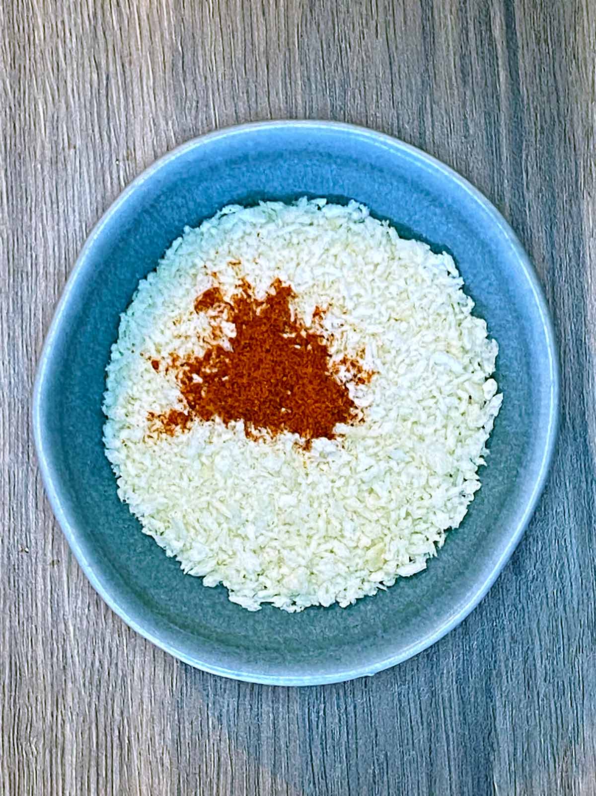 A bowl containing breadcrumbs and paprika.