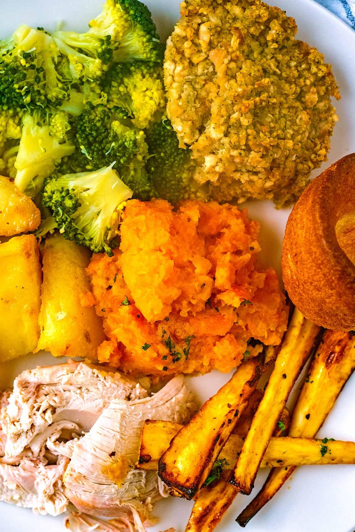 Carrot and swede mash on a plate with roast chicken, broccoli, potatoes, parsnips and stuffing.