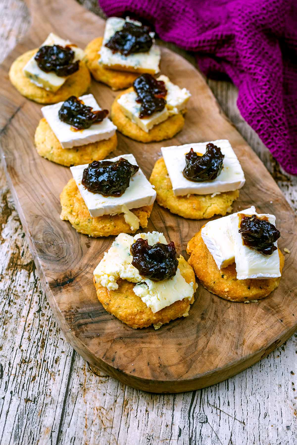 Eight biscuits each topped with cheese and chutney.