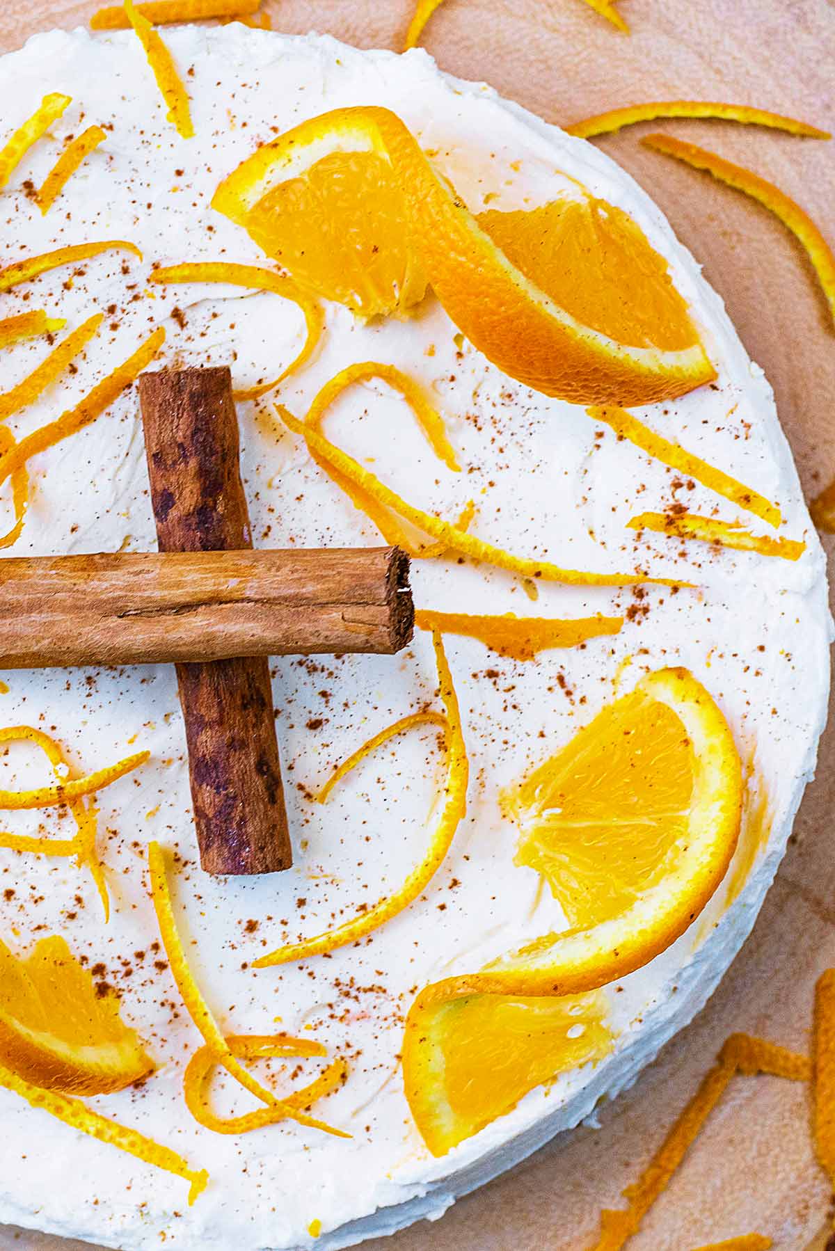Cheesecake on a board topped with oranges and cinnamon.