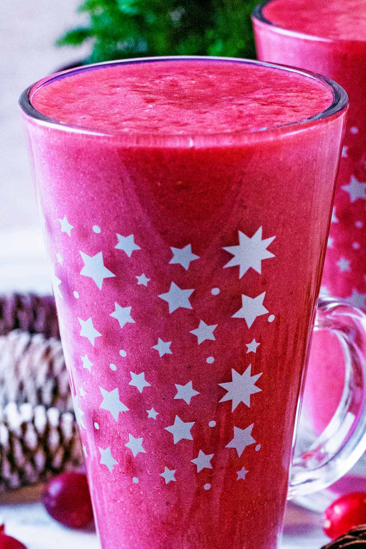 A tall glass decorated with stars containing cranberry smoothie.
