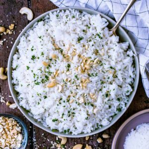 A bowl of coconut rice with chopped cashews sprinkled over it.