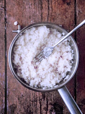 Cooked rice in a pan that has been fluffed up with a fork.