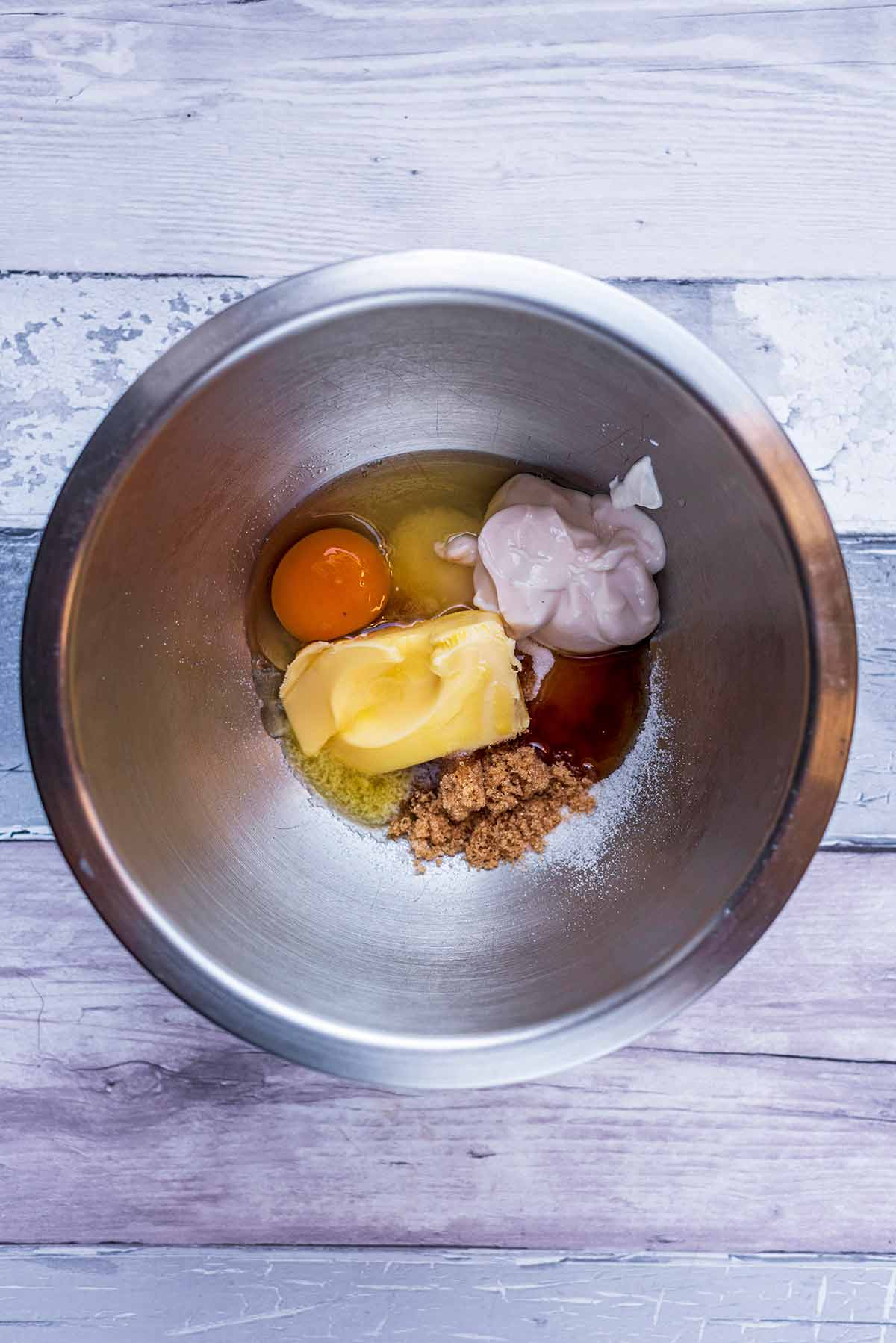 A mixing bowl with sugar, butter, egg, yogurt and vanilla.