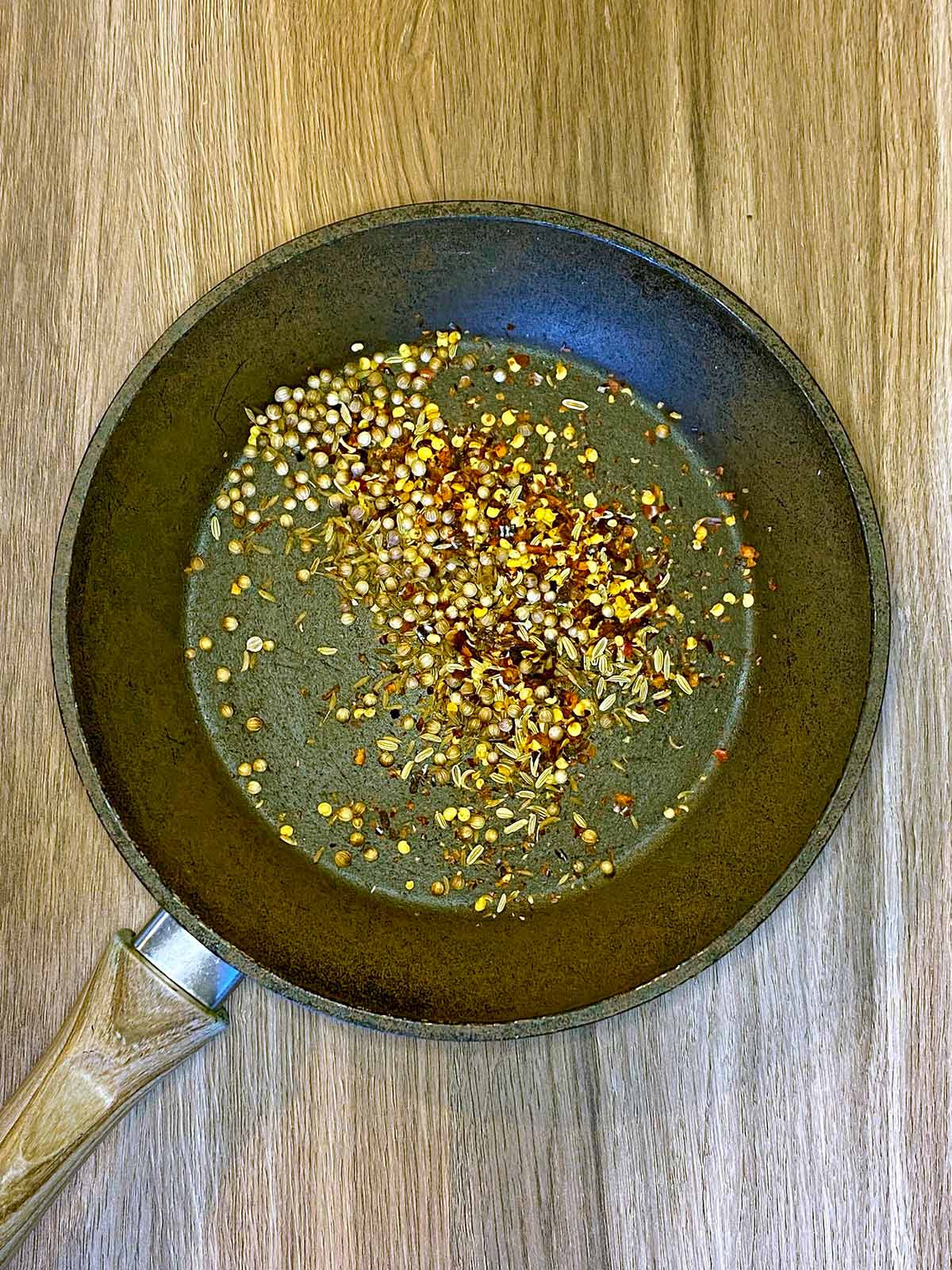 Various seeds toasting in a frying pan.