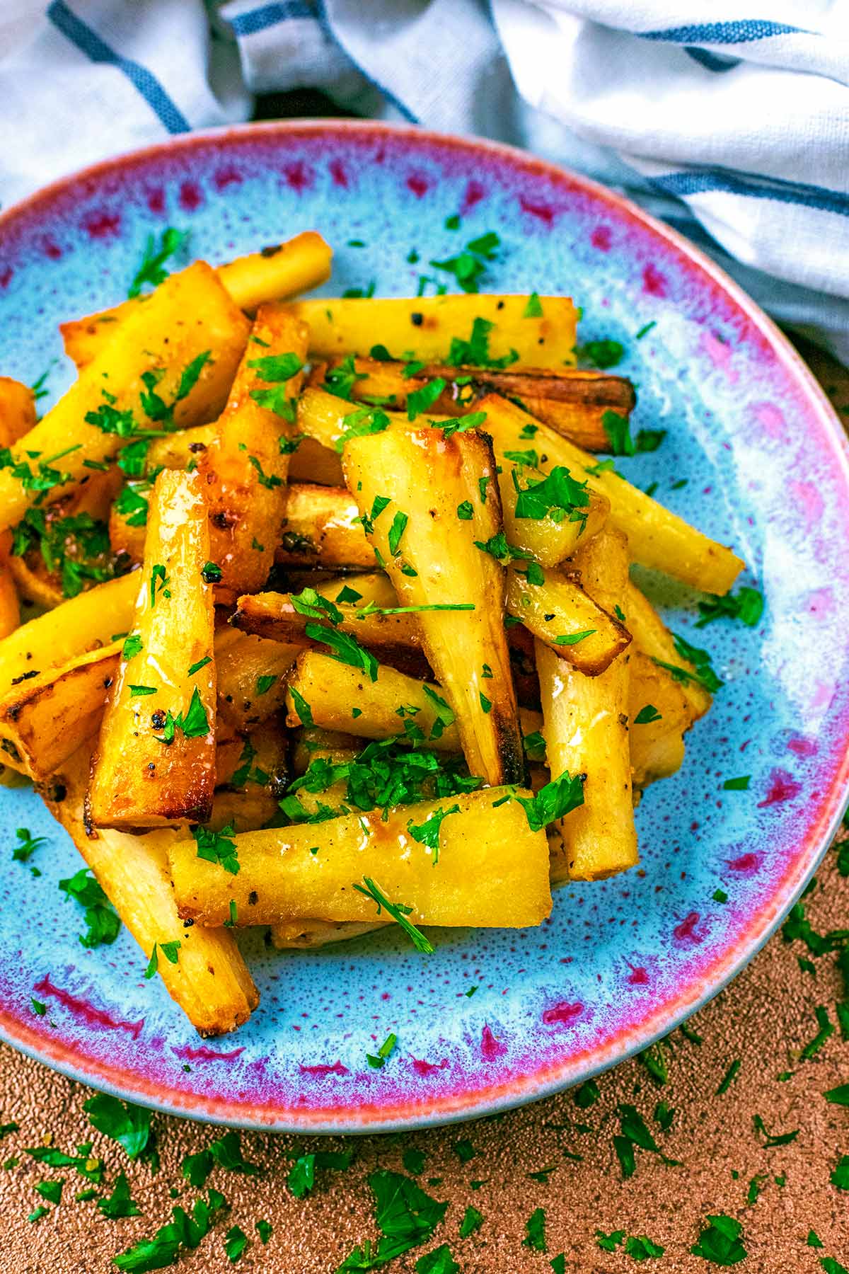 Roast parsnips on a blue patterned plate.