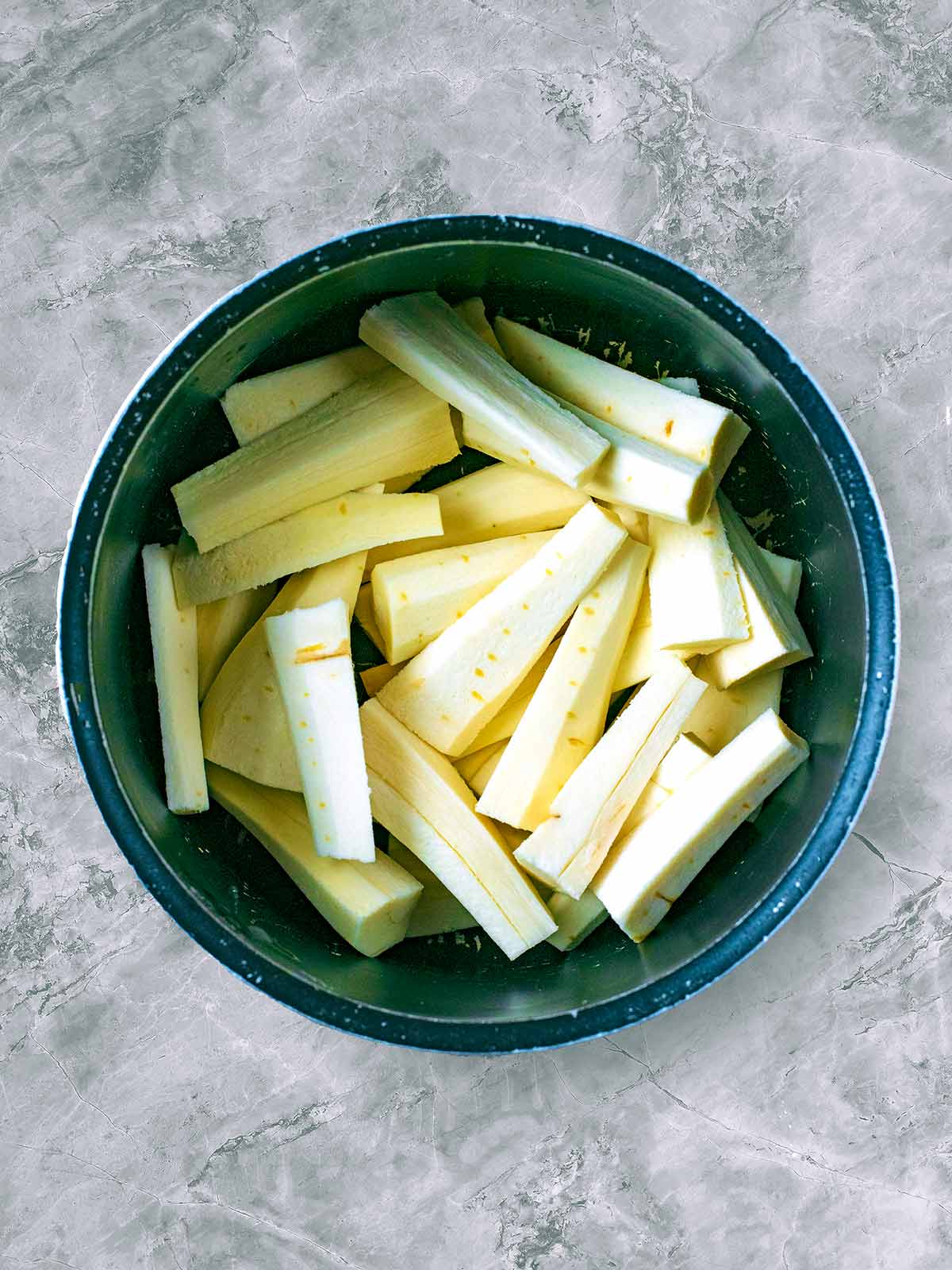 A saucepan of raw chopped parsnips.