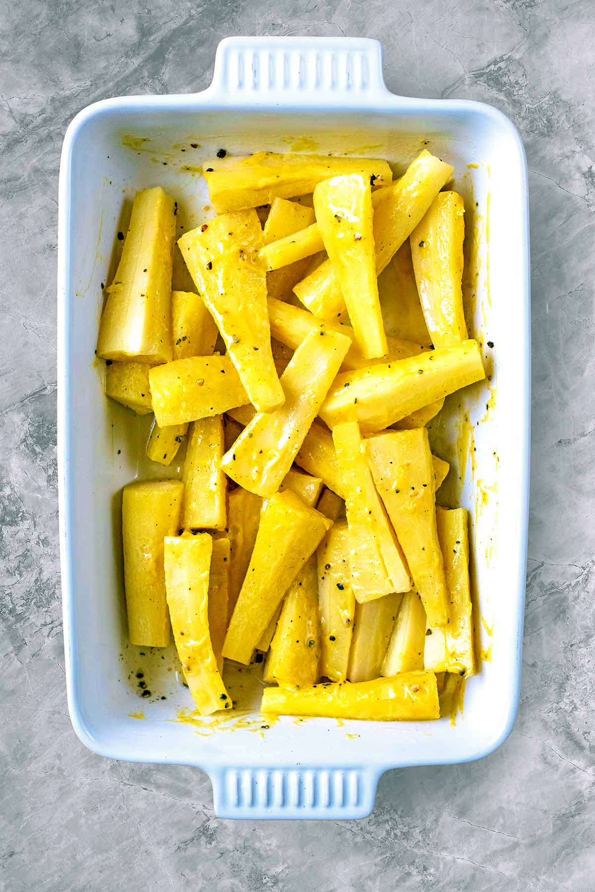 A white baking dish with parboiled parsnips.