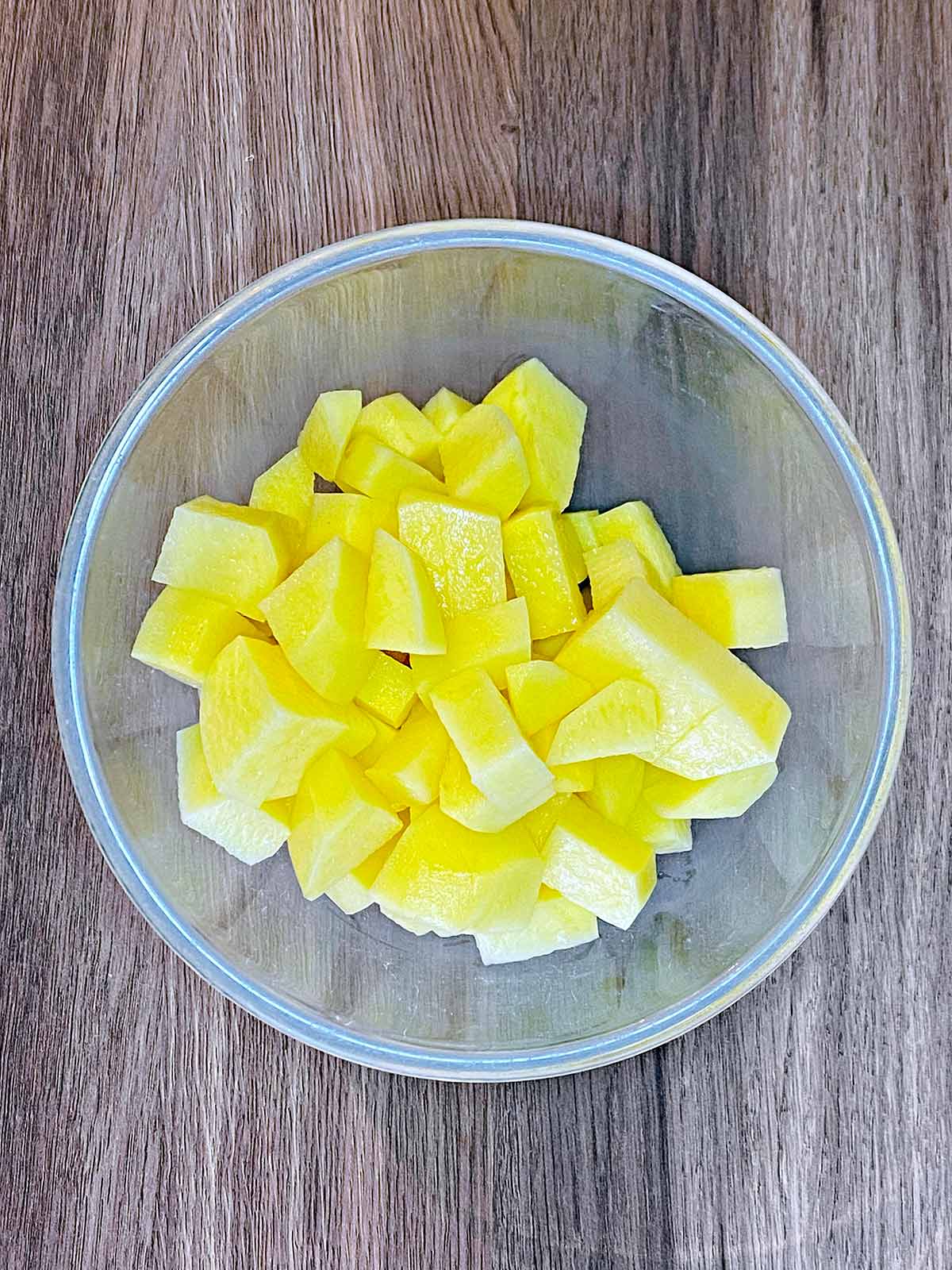 Peeled and chopped potatoes in a glass bowl.