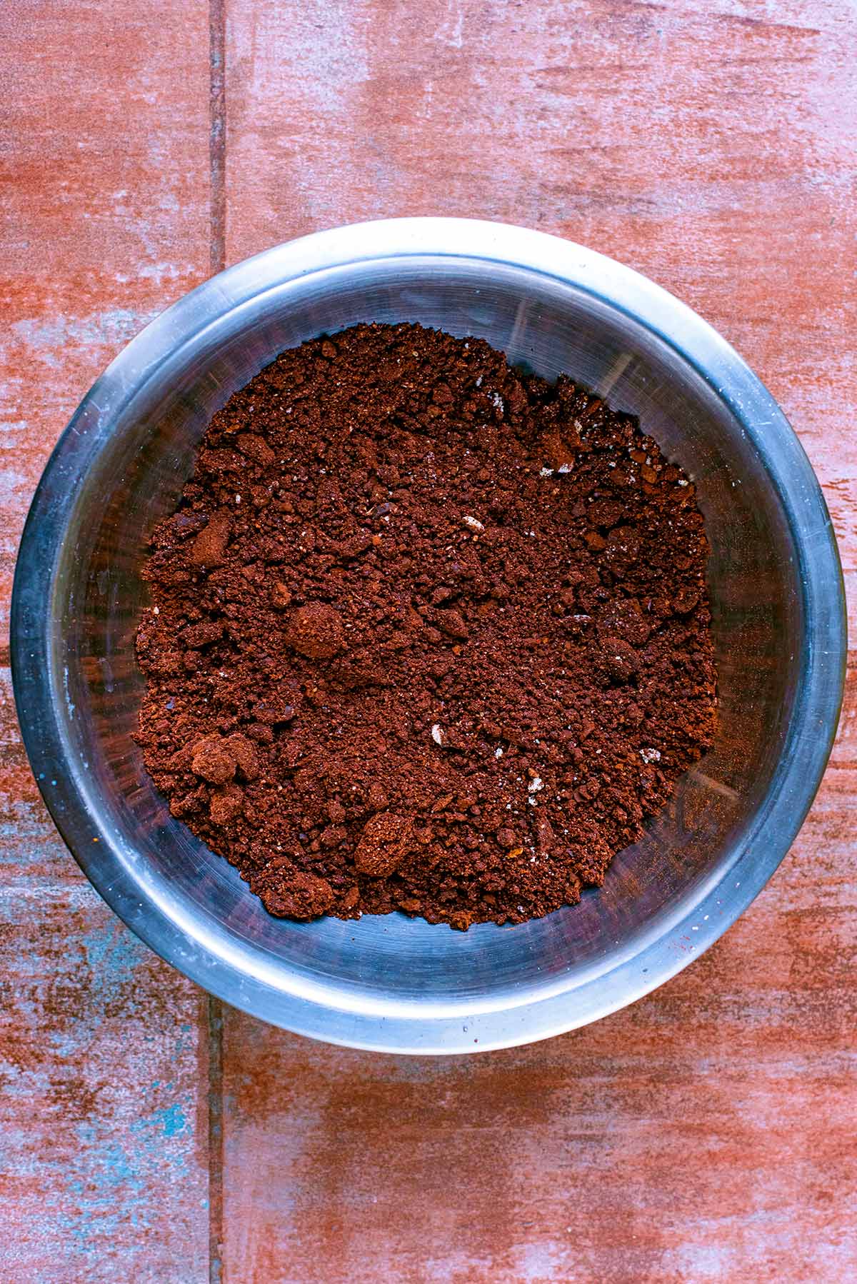 A metal mixing bowl full of ground almonds, chopped dates and cocoa powder.
