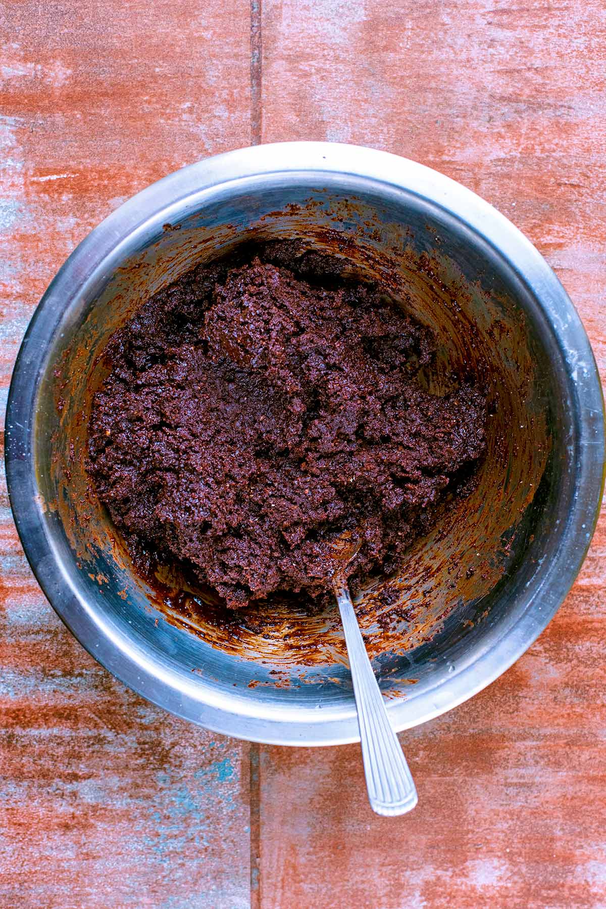 A metal mixing bowl with raw brownie mixture in it.