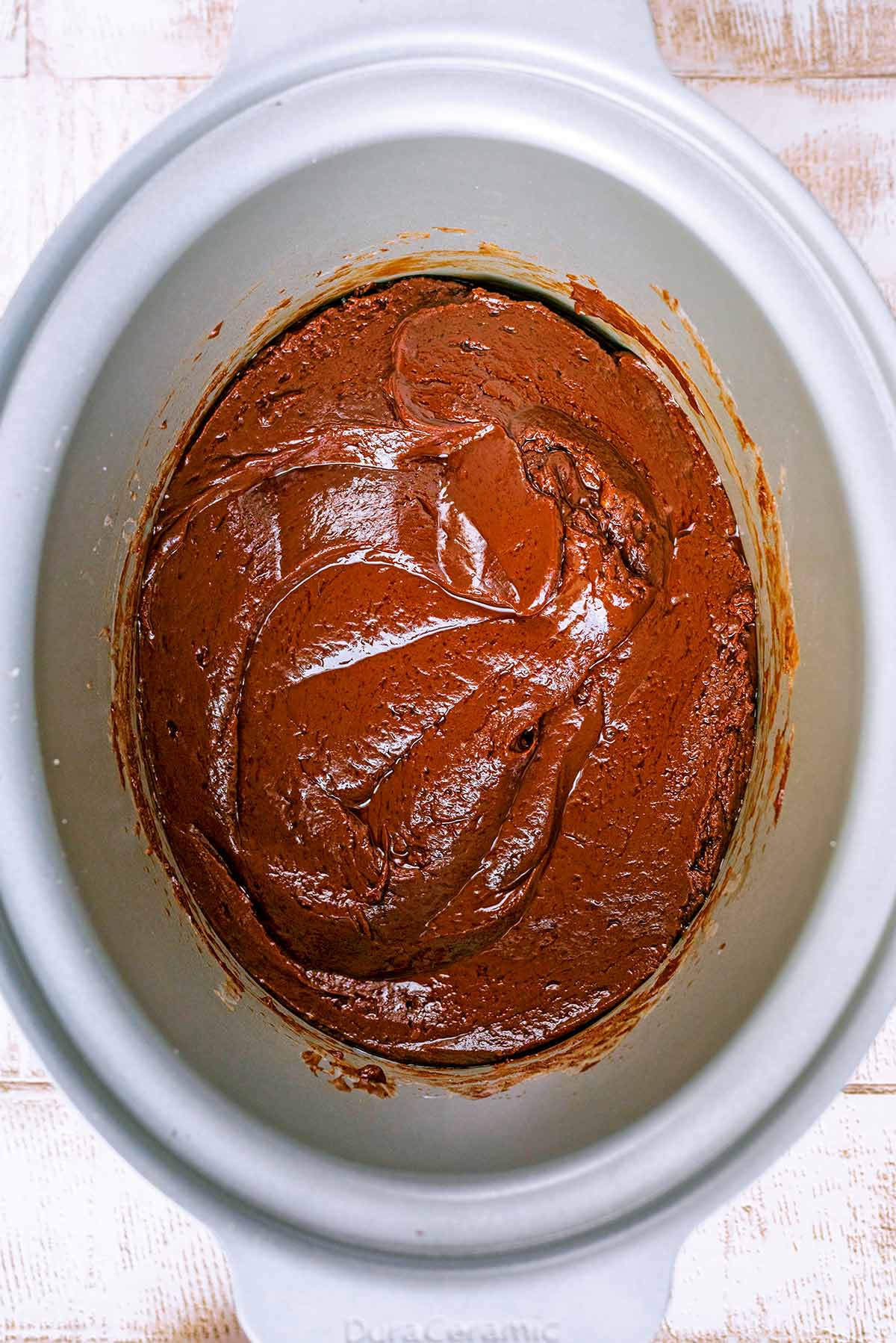 A slow cooker pot containing melted chocolate.