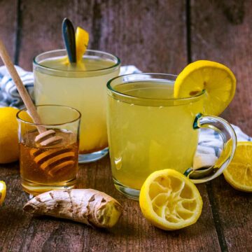 Honey and lemon drink surrounded by honey, lemon and ginger.