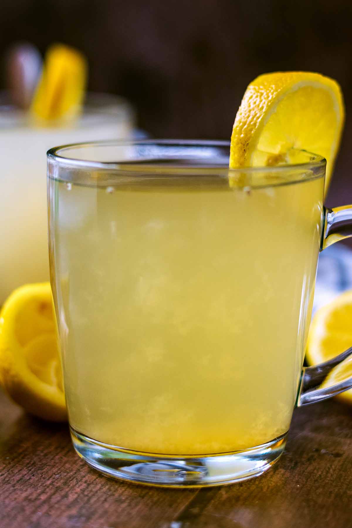 Hot lemon and honey drink in a glass with a lemon slice on top.
