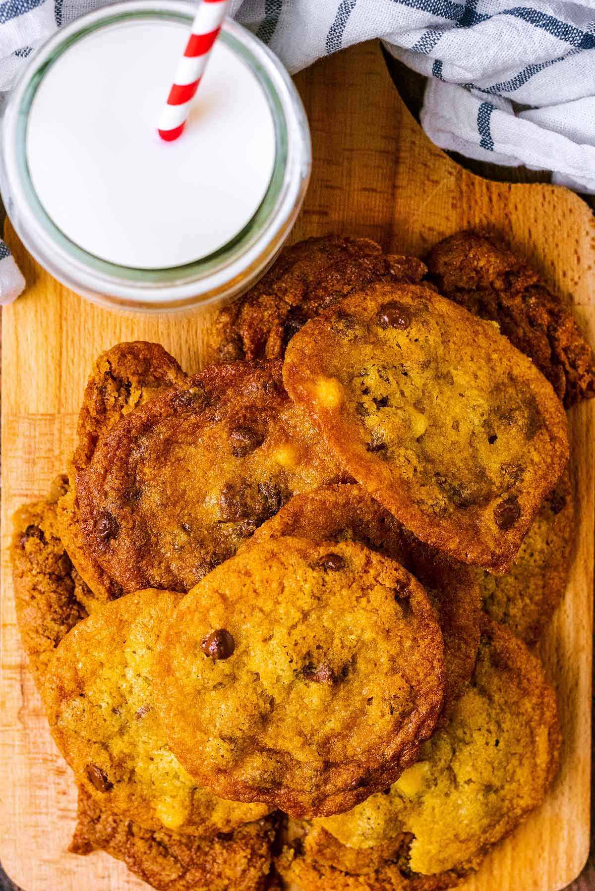 Chocolate chip cookies on a board with a glass of milk.