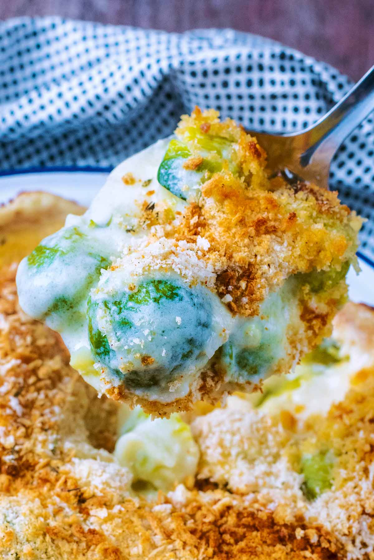 Cheese covered Brussels sprouts on a spoon.
